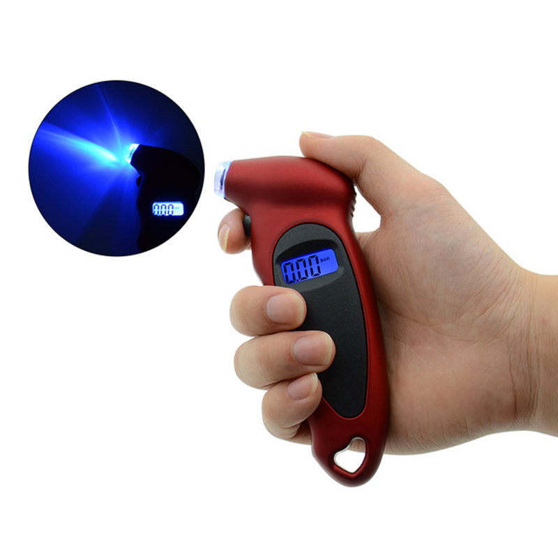 A hand holding a digital tire pressure gauge with a blue LCD screen, against the backdrop of a car tire.