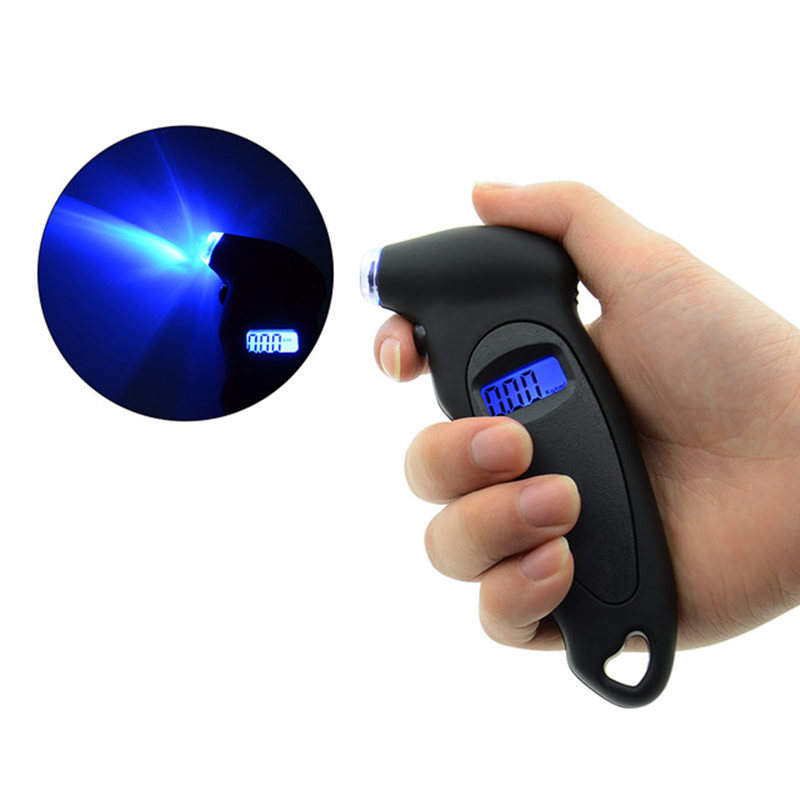 A hand holding a digital tire pressure gauge with a blue LCD screen, against the backdrop of a car tire.